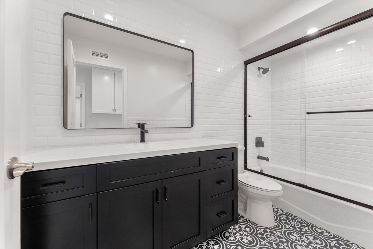 the upstairs guest bathroom. features floor to ceiling beveled subway tile, a glass shower door, plenty of storage, and a sleep contemporary design.